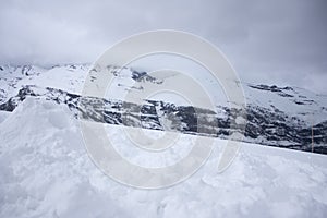 Before the storm in the Andes mountains the fog descends to the rocky mountains covered with snow