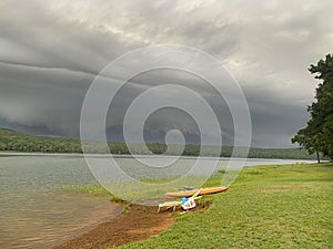 Storm approaches the lake and beach with kayak and beach chair