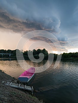 Storm arcus shaft and cumulonimbus cloud with heavy rain or summer shower, severe weather and sun glow behind rain. Landscape with