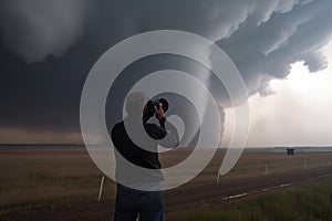 storm chaser, with camera in hand, capturing up-close shots of tornado touching down