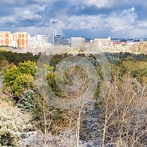 Storm clouds over city and first snow on woods