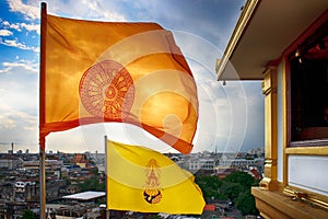 Storm clouds over the Dharmachakra flag and HM King Bhumibol Adulyadej flag on top of the phu khao thong Bangkok Thailand