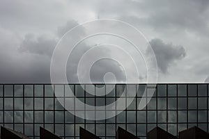 Storm clouds reflect in windows of office building/ Mirror windows with overcast sky reflections/ corporate building facade