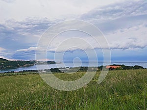 Storm clouds running across the sky against the background of the sea and green hills on coast. Scenic view to Adriatic sea