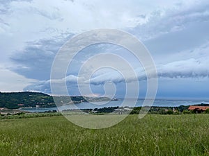 Storm clouds running across the sky against the background of the sea and green hills on coast. Scenic view to Adriatic sea