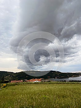 Storm clouds running across the sky against the background of the sea and green hills on coast. Scenic view to Adriatic sea