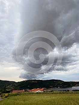 Storm clouds running across the sky against the background of the sea and green hills on coast. Scenic view to Adriatic sea