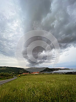 Storm clouds running across the sky against the background of the sea and green hills on coast. Scenic view to Adriatic sea