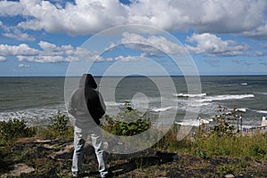 The storm is coming. A lonely man is standing up in front of Baltic sea which is making waves