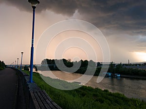 Storm cumulonimbus cloud with heavy rain or summer shower, severe weather and sun glow behind rain.