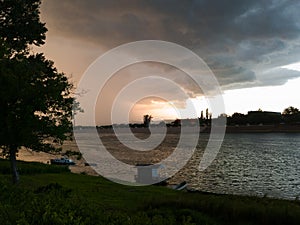 Storm cumulonimbus cloud with heavy rain or summer shower, severe weather and sun glow behind rain.