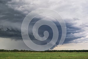 Storm cyclone over summer fields, hills and forests