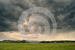 Storm cyclone over summer fields, hills and forests