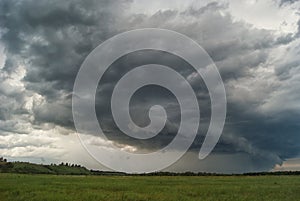 Storm cyclone over summer fields, hills and forests