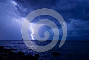 A storm front with rain and curved lightning striking the sea near an abandoned marine science platform