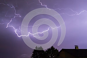 Storm with lightnings, a house and trees