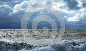 Storm in the ocean. Cloudy gloomy sky and high waves of the surf