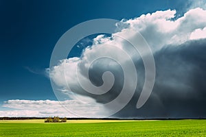 Storm And Rain Above Countryside Rural Field Or Meadow Landscape With Green Grass Under Scenic Spring Blue Dramatic Sky