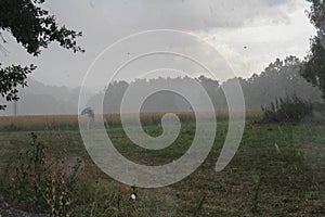 Storm rainy weather in Czech landscape, man with umbrela