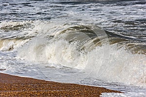 Storm at sea, big foamy waves breaking on shore