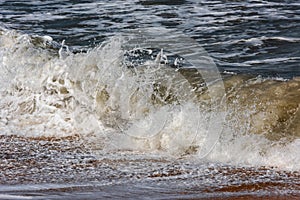 Storm at sea, big foamy waves breaking on shore