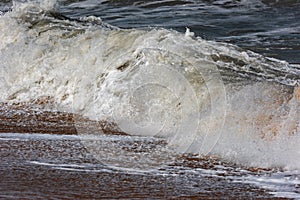 Storm at sea, big foamy waves breaking on shore