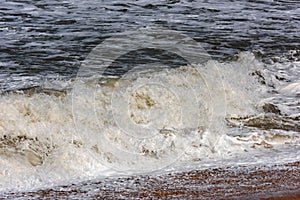 Storm at sea, big foamy waves breaking on shore