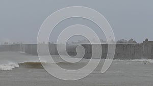 Storm sea waves break against harbours sea wall