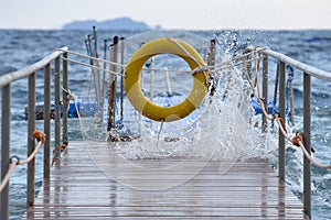 Storm on the sea. Waves crash on a wooden pier and Lifebuoy, water splashes