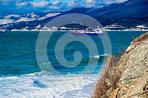 During the storm, the ships are on the roadstead of the port of Novorossiysk. The Caucasus mountains are in the background