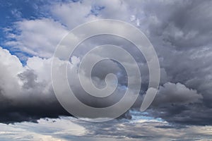 Storm sky. Dark grey big cumulus clouds against blue sky background, cloud texture, thunderstorm