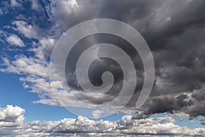 Storm sky. Dark grey and white big cumulus clouds against blue sky background, cloud texture