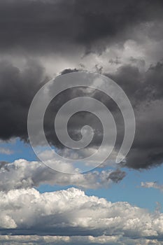 Storm sky. Dark grey and white big cumulus clouds against blue sky background, cloud texture, thunderstorm