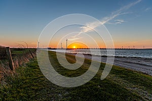 A storm surge barrier and windmills in Zeeland province in the Netherlands on sunset