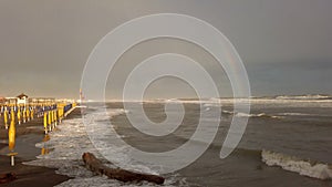 A storm surges down on the coasts with rough sea and beautiful rainbow