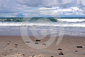 Storm weather on Baltic sea, landscape with sand beach with focus on front stones