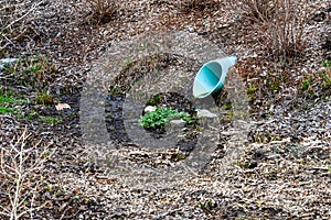 Stormwater collection blue PVC pipe running into a mostly dry water retention pond, winter landscape