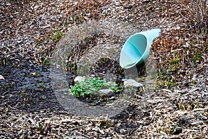 Stormwater collection blue PVC pipe running into a mostly dry water retention pond, winter landscape