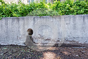 Stormwater drain outlet in an urban area with seepage discoloring a concrete barrier