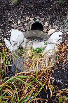 Stormwater management, outlet pipe for excess rainwater, sandbags, and garden plantings