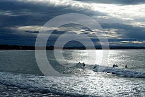 Stormy Beach - surfer silhouettes under a dramatic dark stormy sky