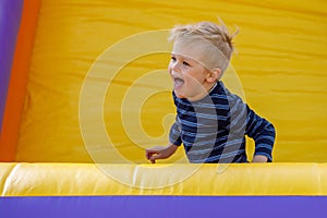 Stormy child be naughty on playground trampoline. Little cool boy have fun on a yellow inflatable trampoline