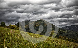 Stormy clouds on the sky over autumn country with meadow and hill at background