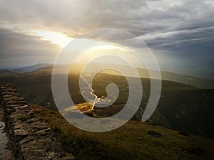 Stormy clouds with sun rays above mountains