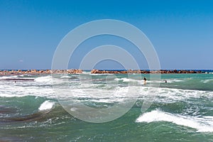 Stormy coastline of Santorini island with surfer on waves