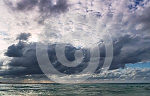 Stormy dark clouds above the sea with sandy beach and curling waves