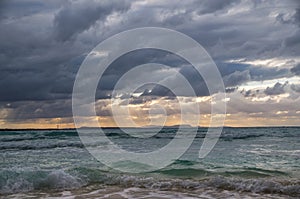 Stormy dark clouds above the sea with sandy beach and curling waves