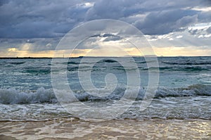 Stormy dark clouds above the sea with sandy beach and curling waves