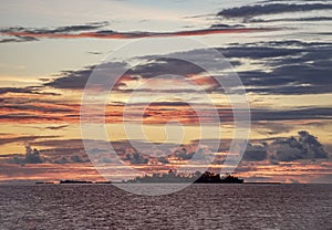 Stormy evening sky painted in stunning colors at sunset in the Indian ocean with silhouette of island