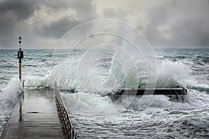 Stormy ocean waves splashing over a pier during a winters storm